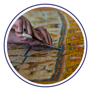 Hand repairing detailed patterned rug with scissors.